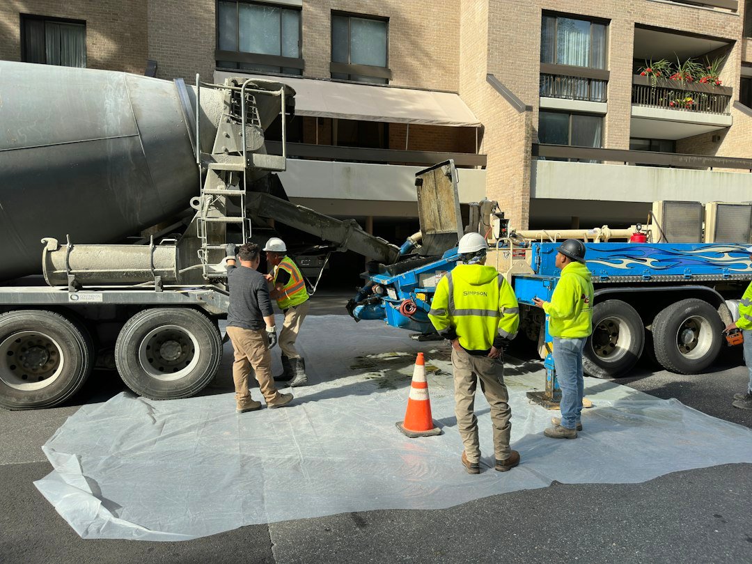 Workers handling freshly mixed concrete at a pump